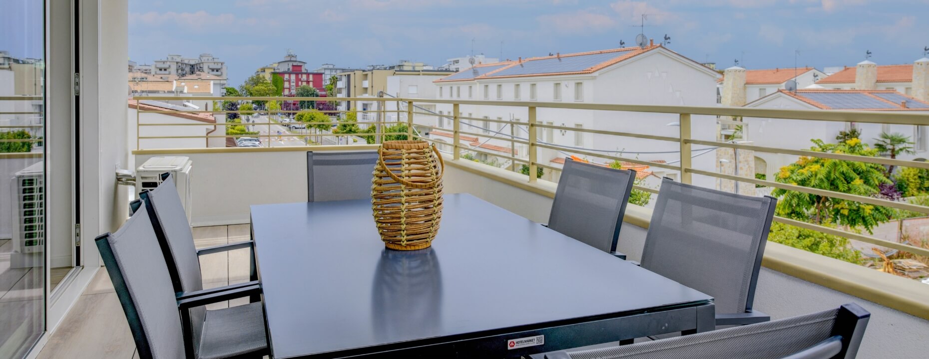 Balcone con tavolo grigio scuro, sedie e logo "HOTELMARKET".