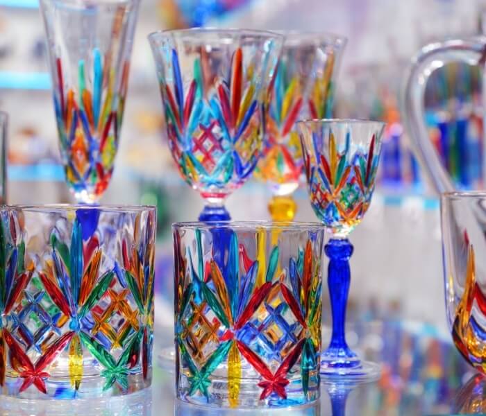 Collezione di bicchieri decorati con motivi colorati e steli blu.