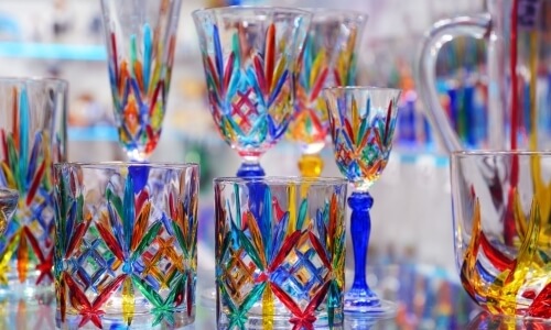 Collezione di bicchieri in vetro con motivi colorati e sfondo sfocato.