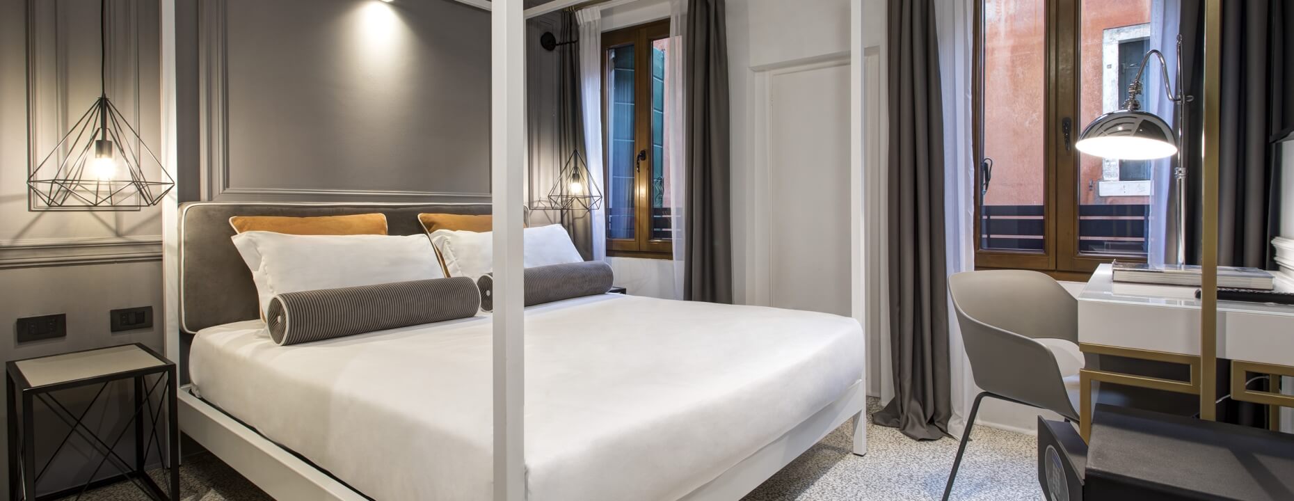 Camera d'hotel con letto a baldacchino e arredi moderni.