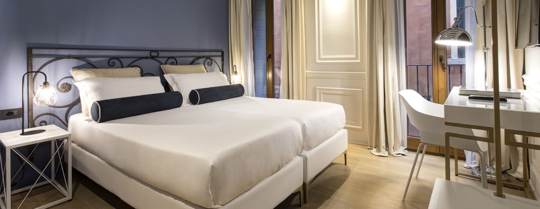 Camera d'hotel con letto grande, scrivania e tende bianche.