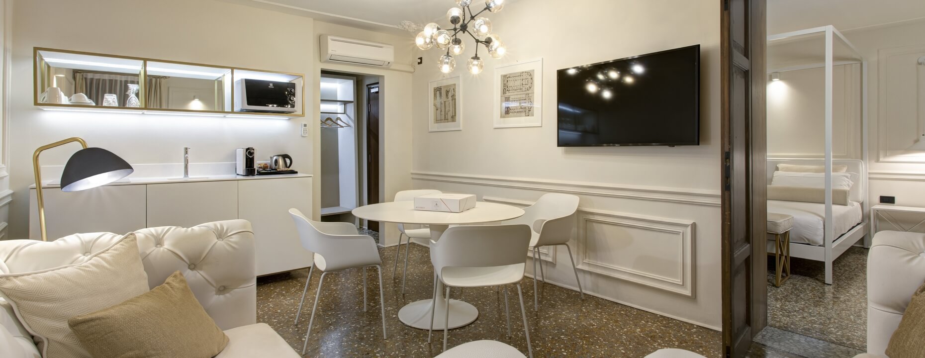 Camera d'hotel con divano, angolo cottura e letto a baldacchino.