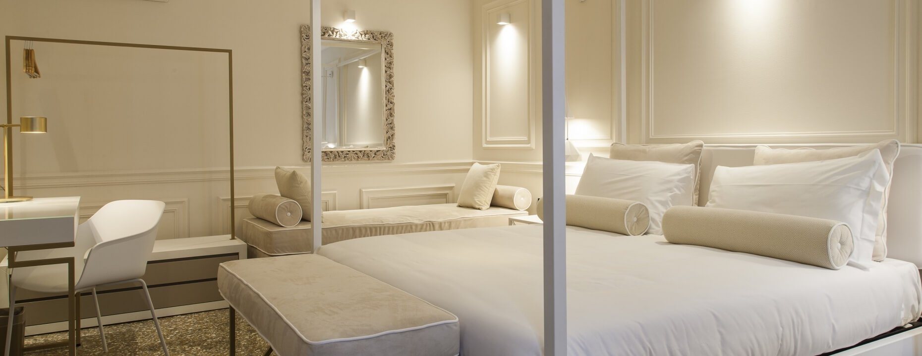 Camera d'hotel elegante con letto, scrivania e divano decorativo.