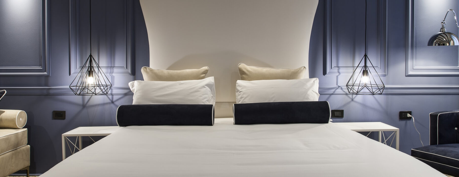Camera d'hotel con letto, divano e poltrona blu.