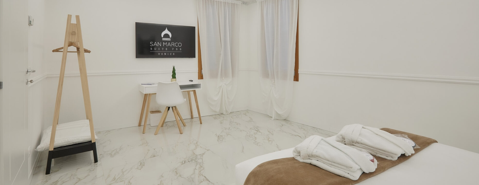 Camera d'hotel con letto, bathrobe, scrivania e televisore.