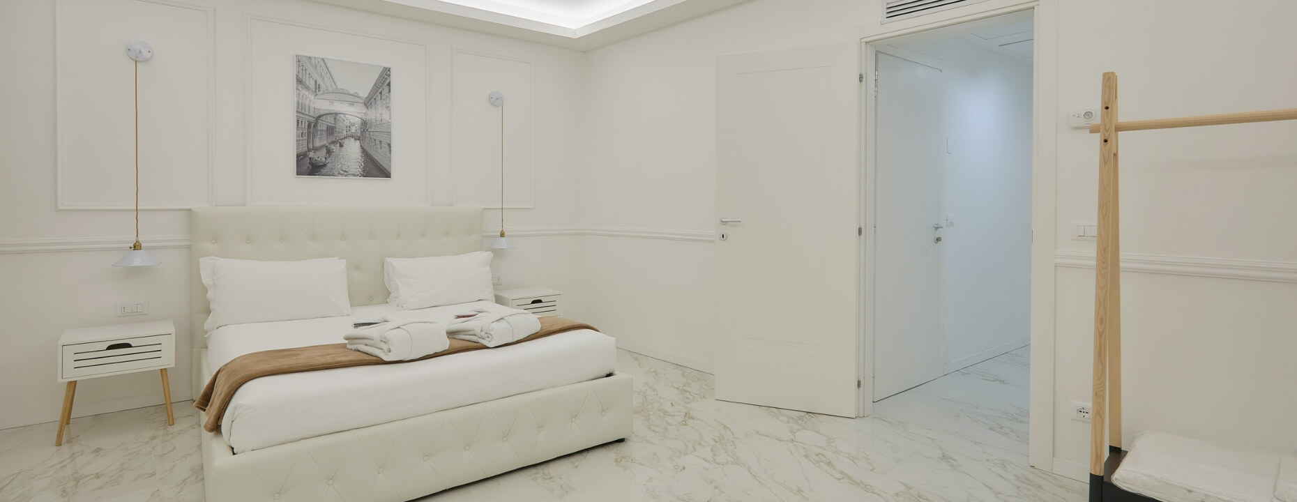 Camera d'hotel con letto king, arredamento bianco e foto di un canale.