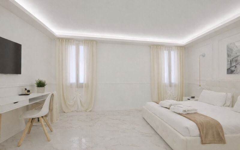 Camera d'hotel con letto, scrivania, TV e finestre con tende.