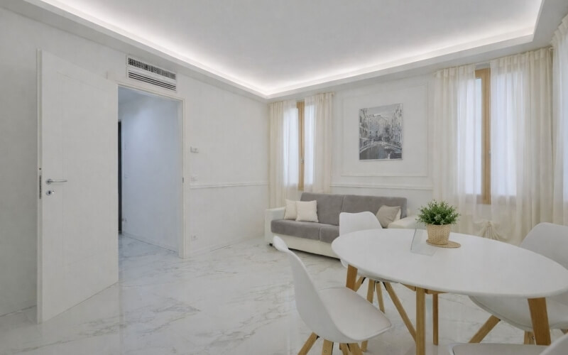 Soggiorno moderno con divano grigio, tavolo ovale e piante.