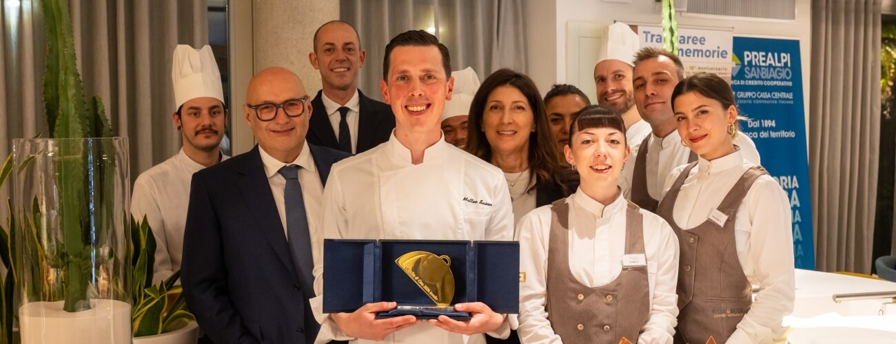 Gruppo di persone con un premio dorato e cappelli da chef.
