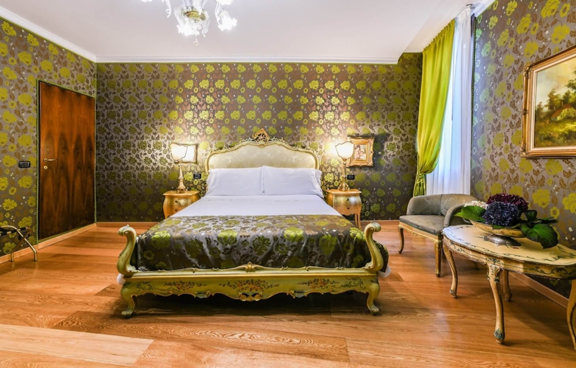 Camera elegante con letto dorato, mobili ornati, pareti floreali e un'atmosfera accogliente.