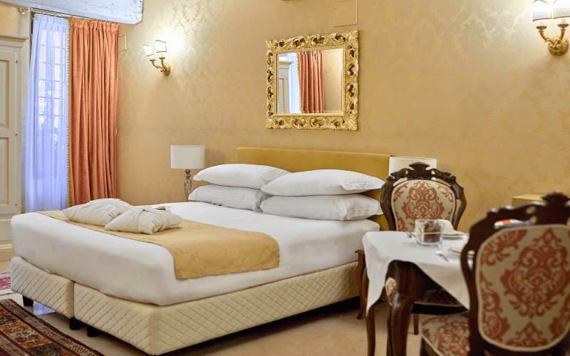 Camera d'hotel con letto, bathrobe, specchio e tavolo.