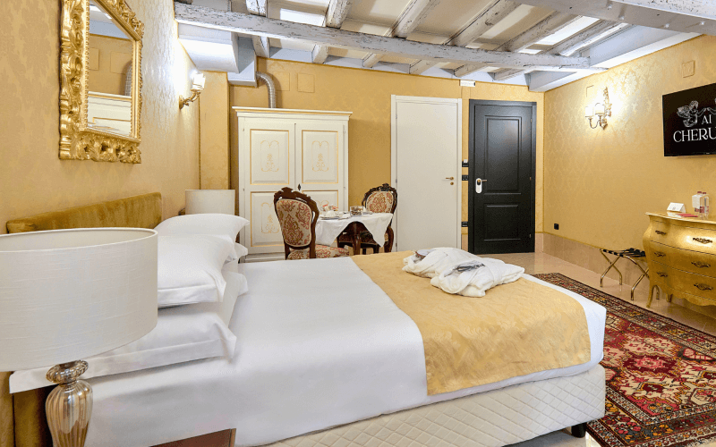 Camera d'hotel con letto bianco, armadio e TV sopra il comò.