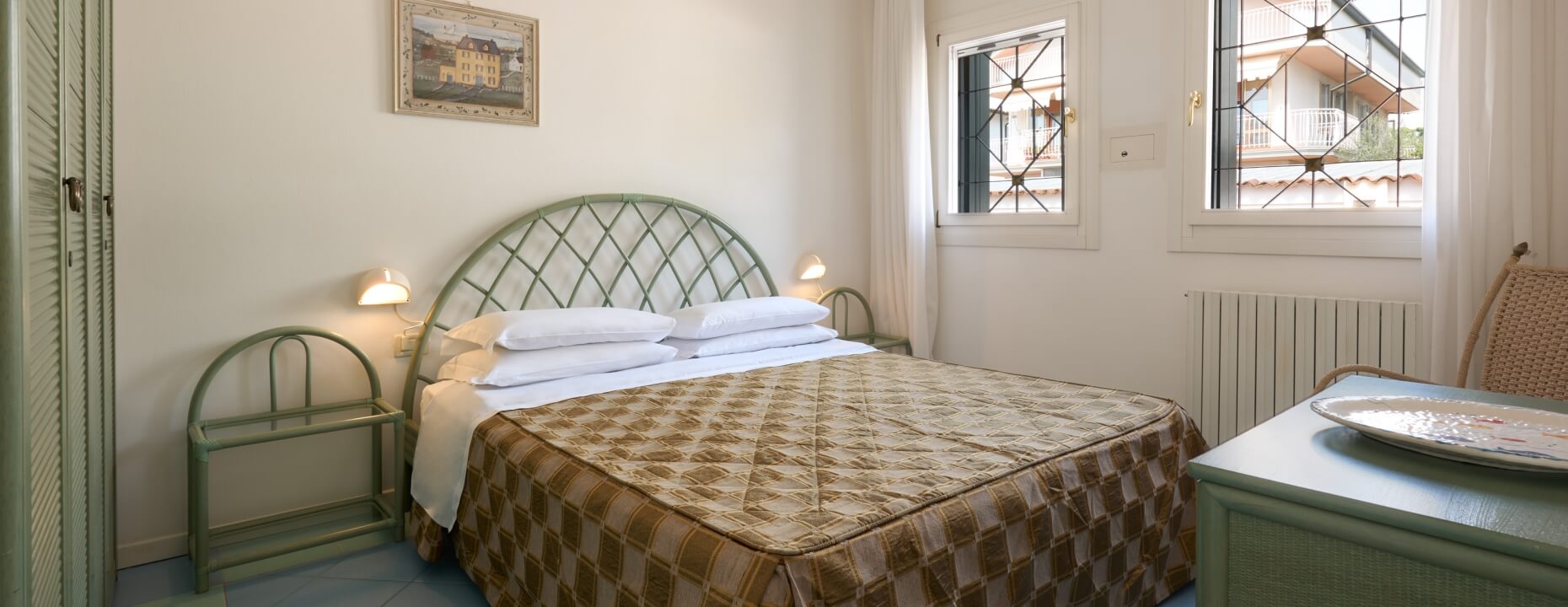 Camera d'hotel con letto, armadio, sedia e decorazioni.