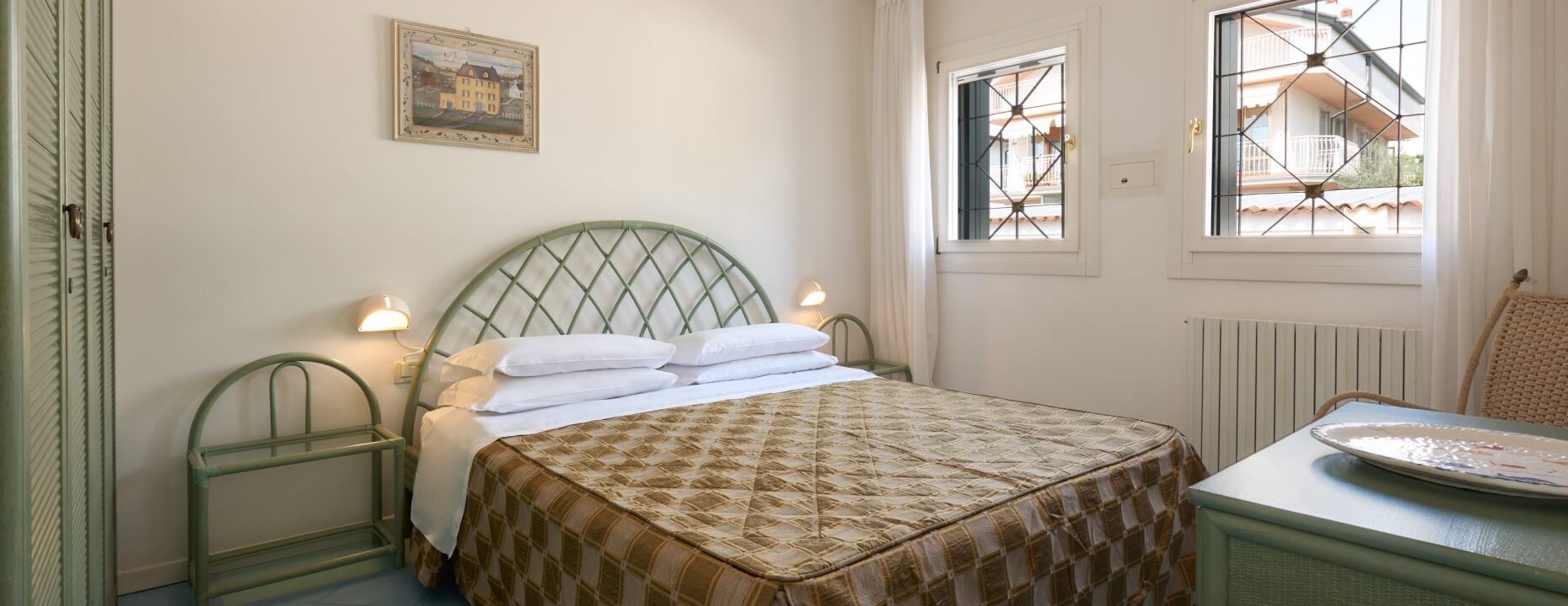 Camera con letto, armadio verde, scrivania e finestre.