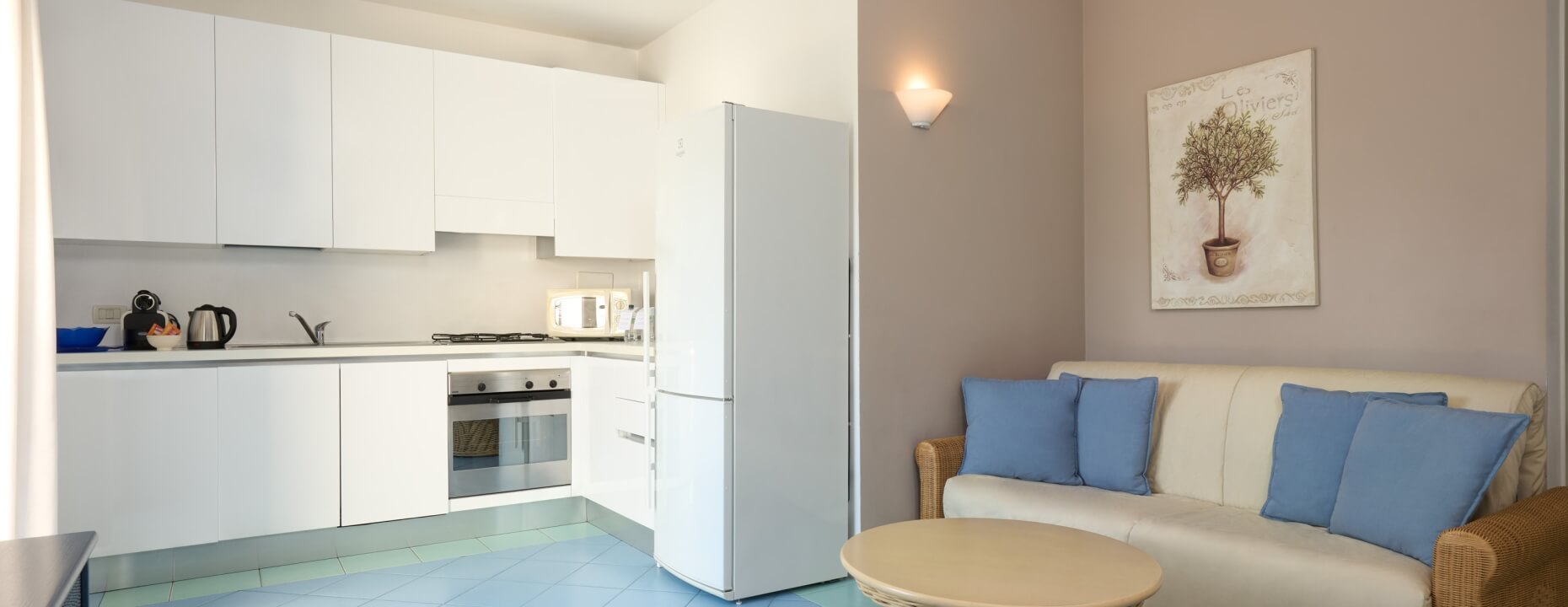 Cucina bianca con soggiorno, divano, poltrona e arte murale.