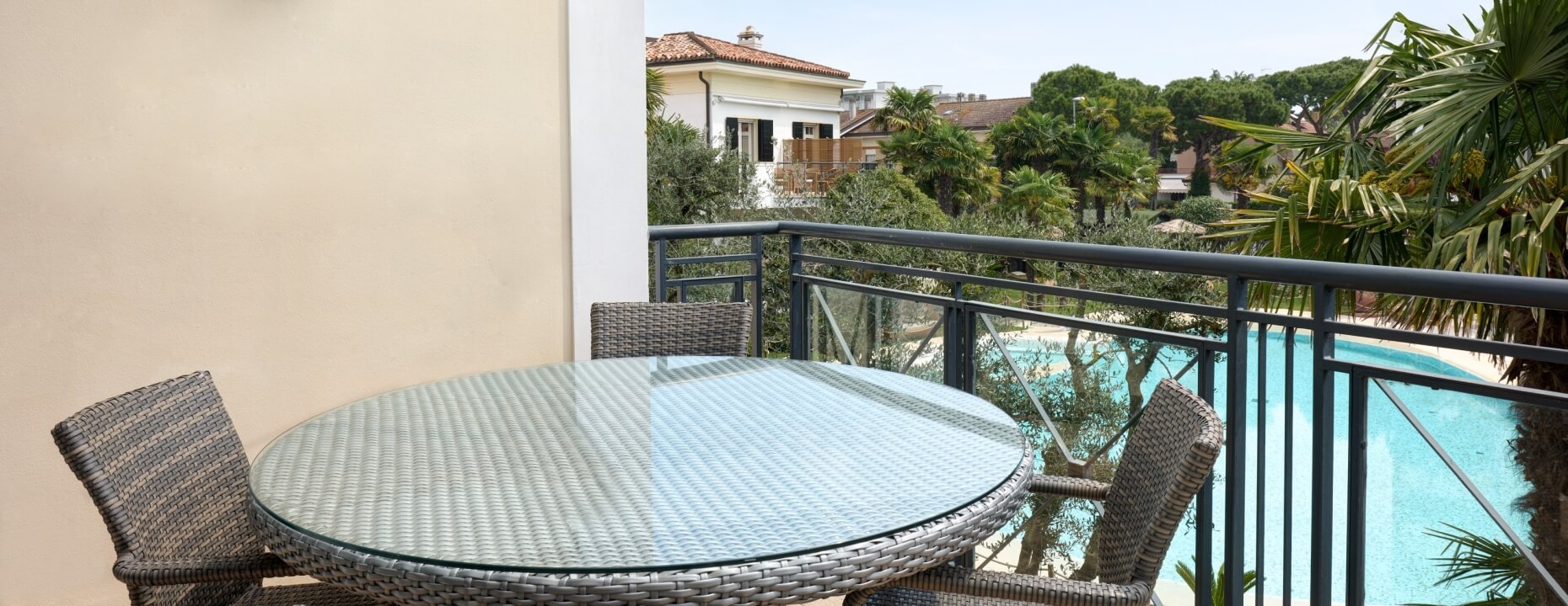 Tavolo rotondo con sedie su un balcone con vista piscina.