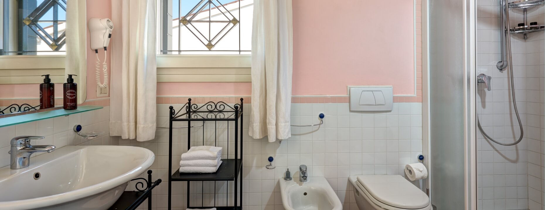 Bagno d'hotel con vasca, doccia, bidet e asciugamani bianchi.