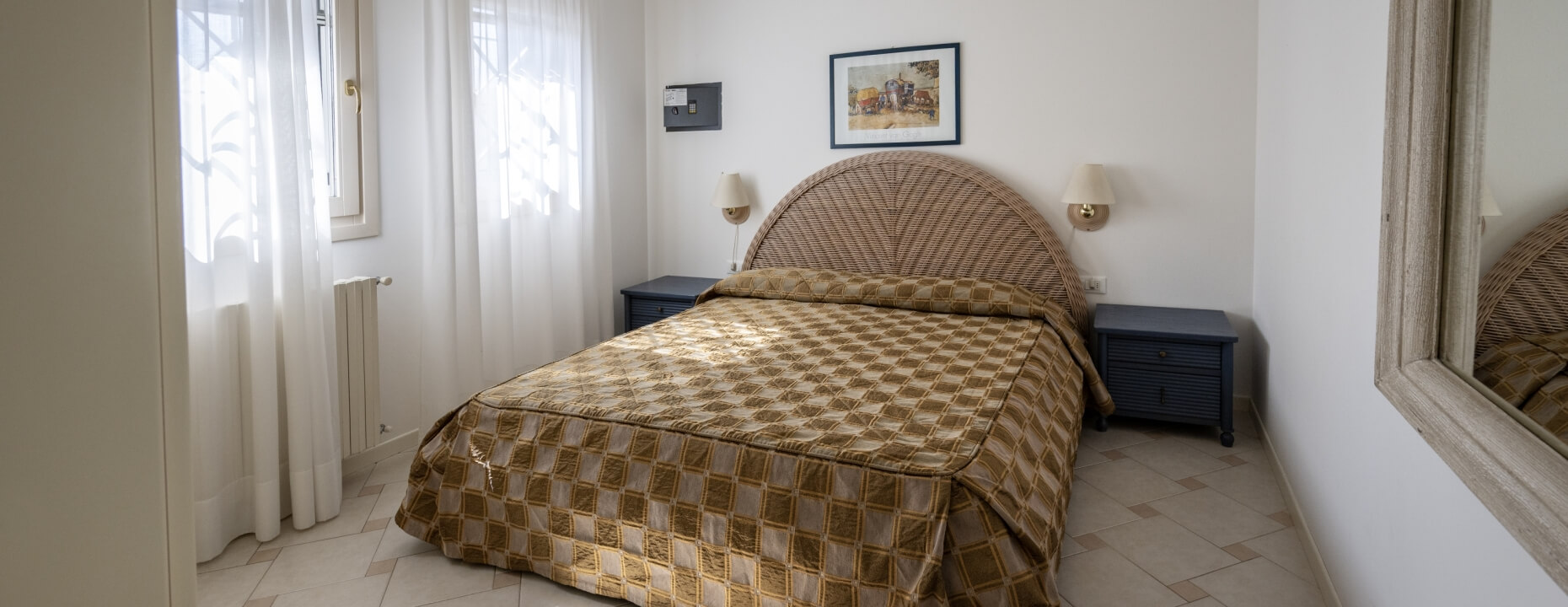 Camera d'hotel con letto matrimoniale, comodini e finestra.