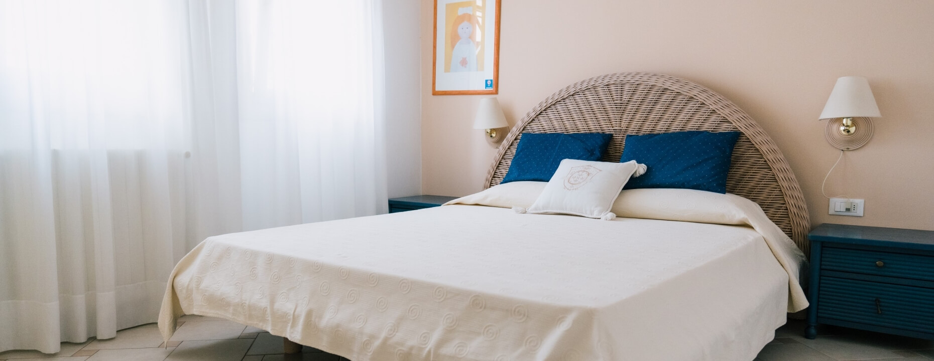 Camera d'hotel con letto matrimoniale, comodini e finestra.