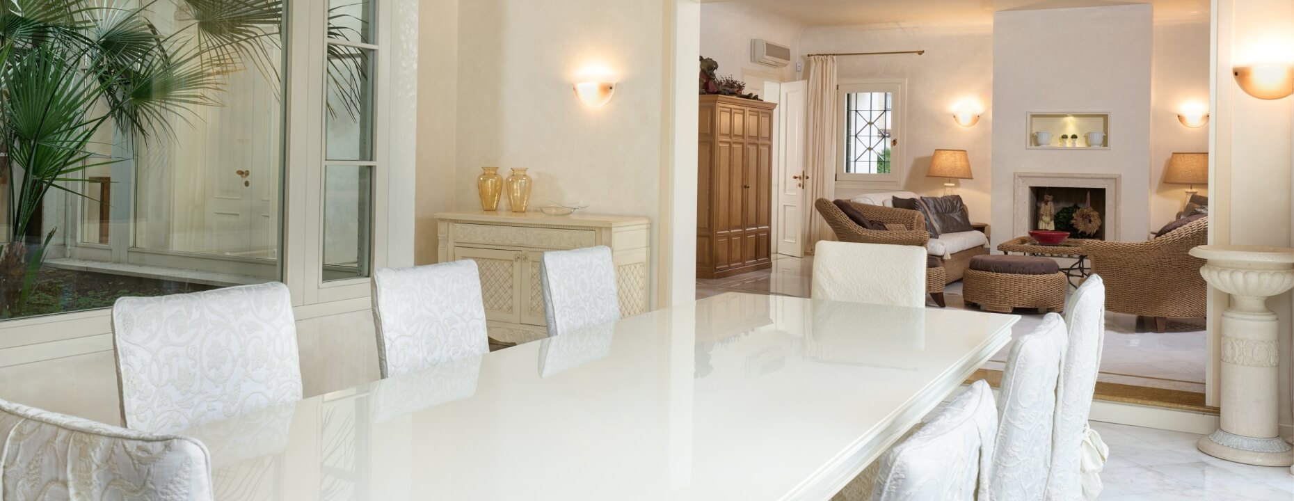 Sala da pranzo con tavolo bianco e area living visibile.