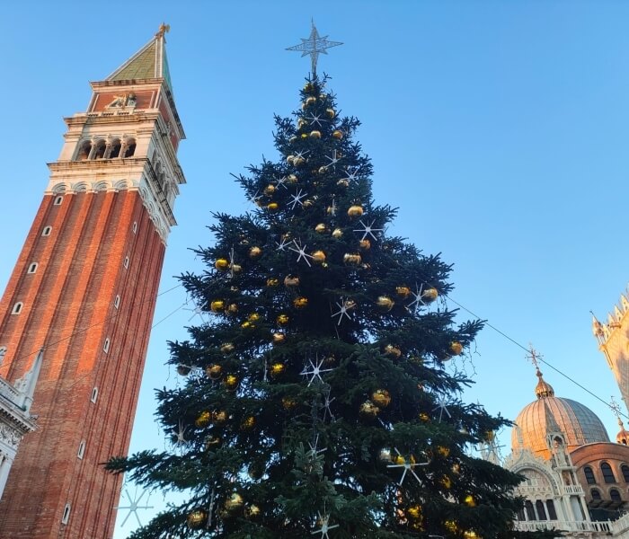 Albero di Natale decorato con edifici architettonici sullo sfondo.