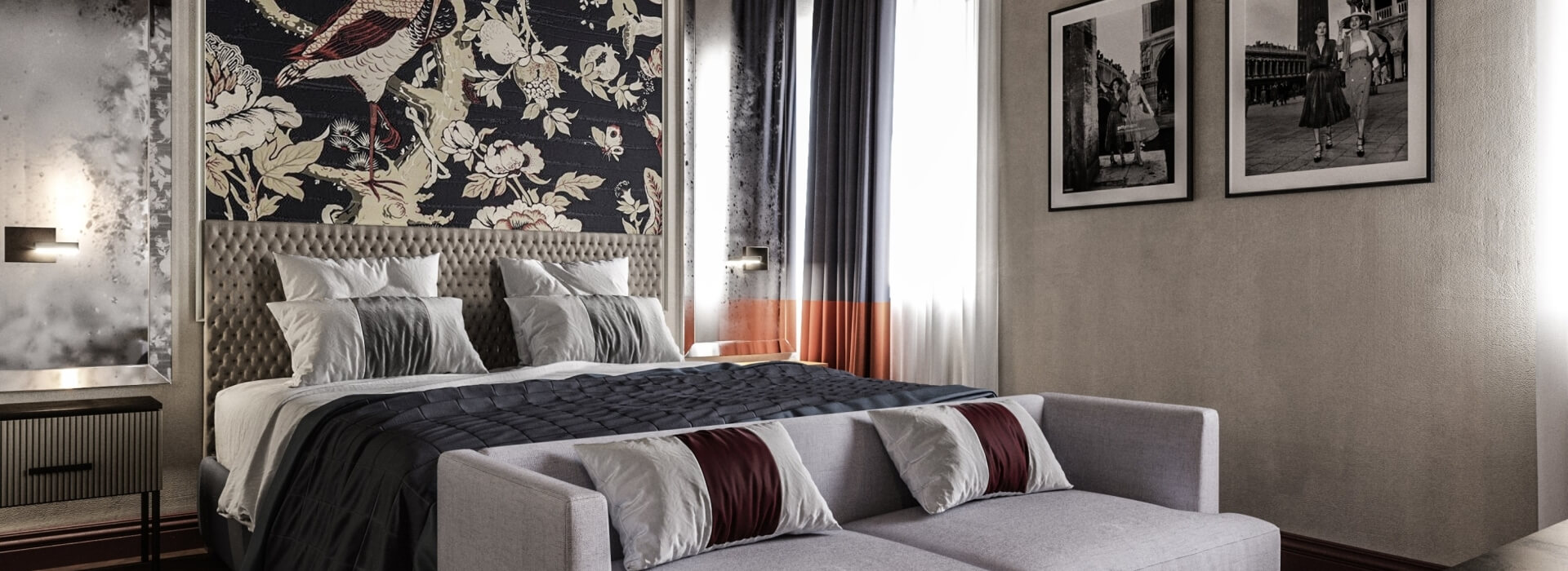 Camera da letto moderna con letto grande, divano grigio, fotografie in bianco e nero e luce naturale che entra dalla finestra.