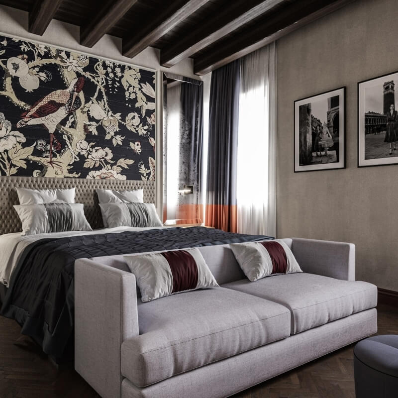 Modern room with floral headboard, white sofa, dark wood floor, and elegant black-and-white photographs on light gray wall.