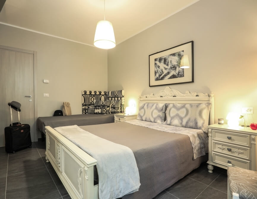 Camera d'hotel con letto, comodini, valigia e decorazioni moderne.