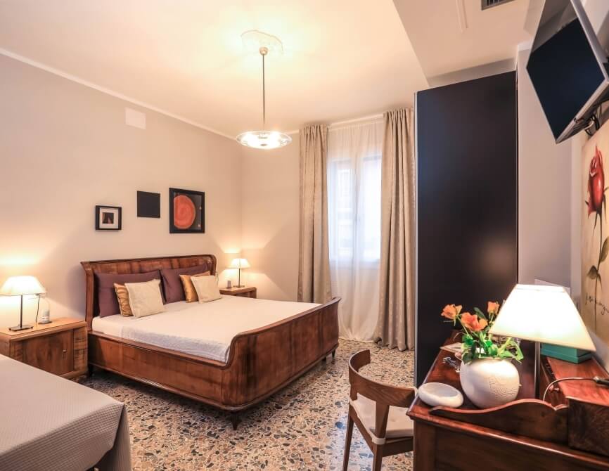 Camera d'hotel con letto, scrivania, sedia e televisore.