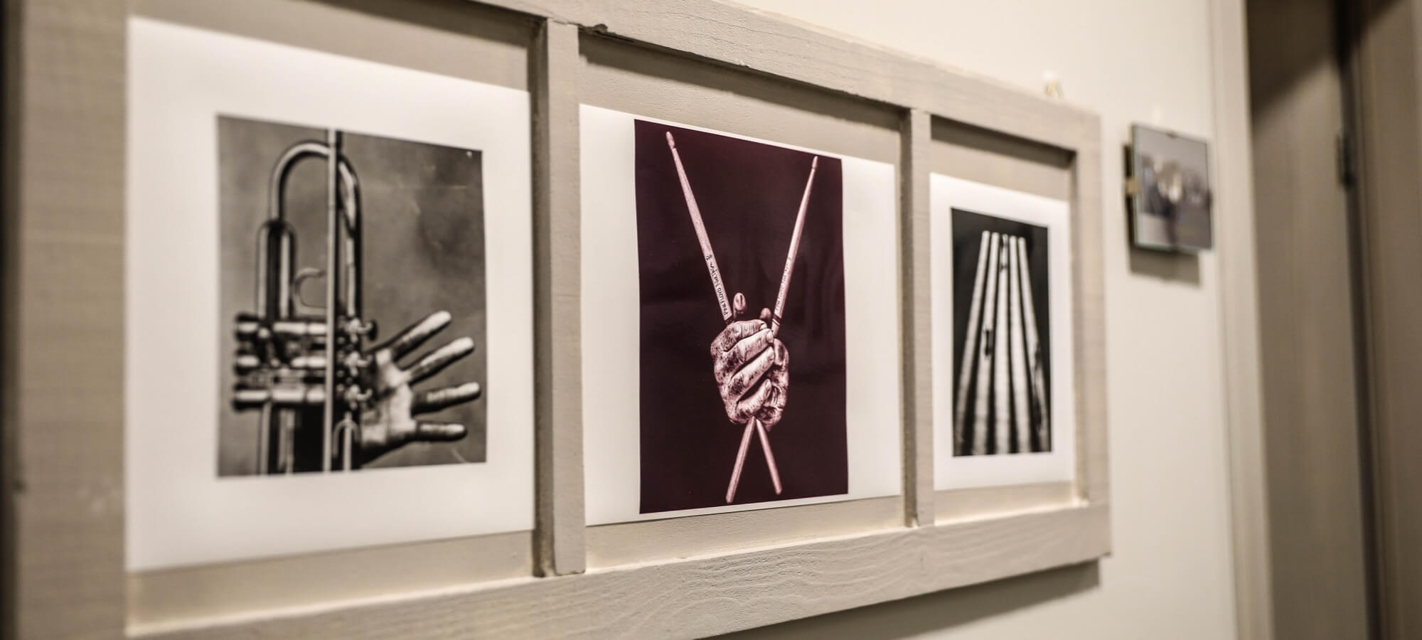 Collezione di tre fotografie incorniciate di strumenti musicali in tonalità seppia su una parete bianca.