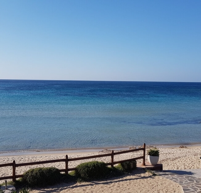 Cielo blu sopra un mare calmo e spiaggia sabbiosa.