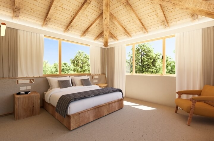 Camera con soffitto in legno, letto bianco e poltrona gialla.