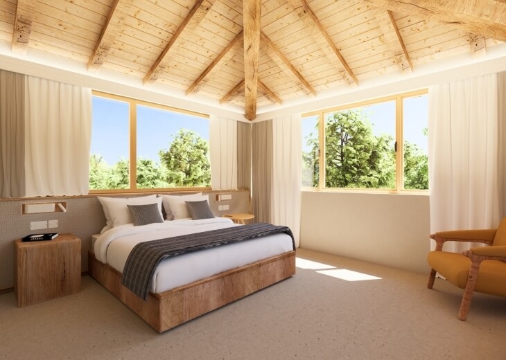 Camera d'hotel con letto, poltrona gialla e finestre luminose.