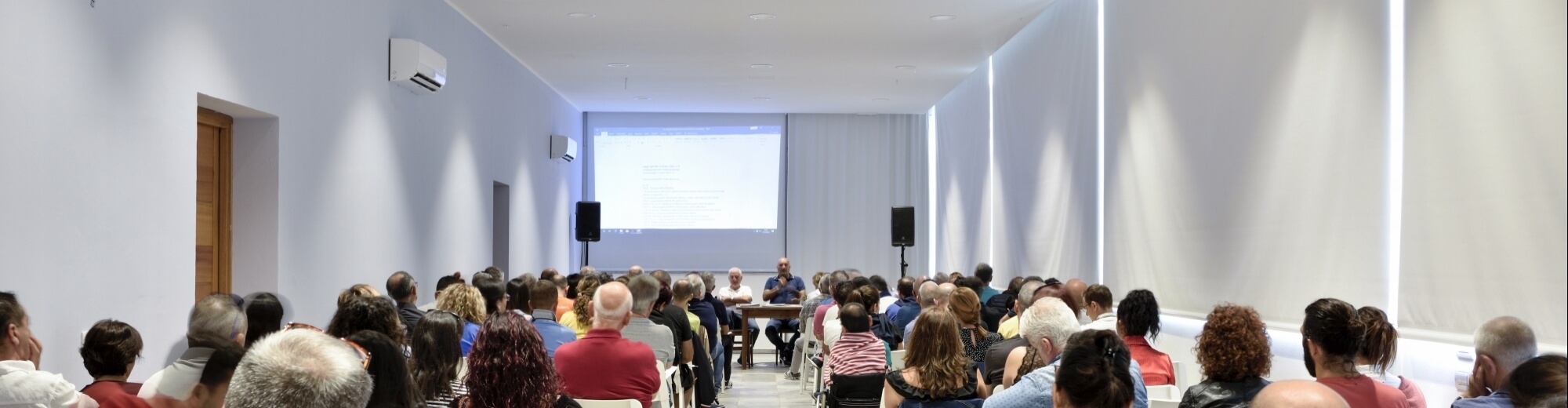 La sala congressi con luci soffuse e videoproiezione