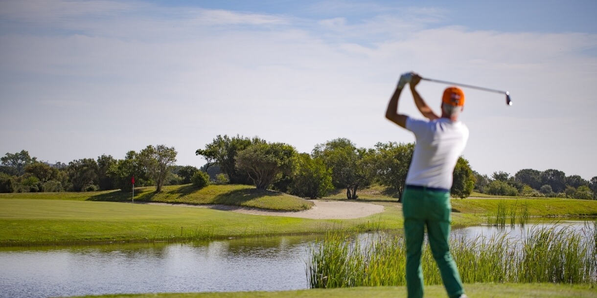 Uomo che lancia davanti al laghetto in campo da golf