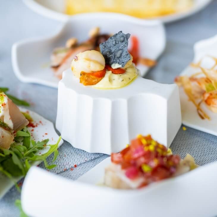 Un antipasto molto elegante, circondato da piatti sfocati di cibo su un tavolo.