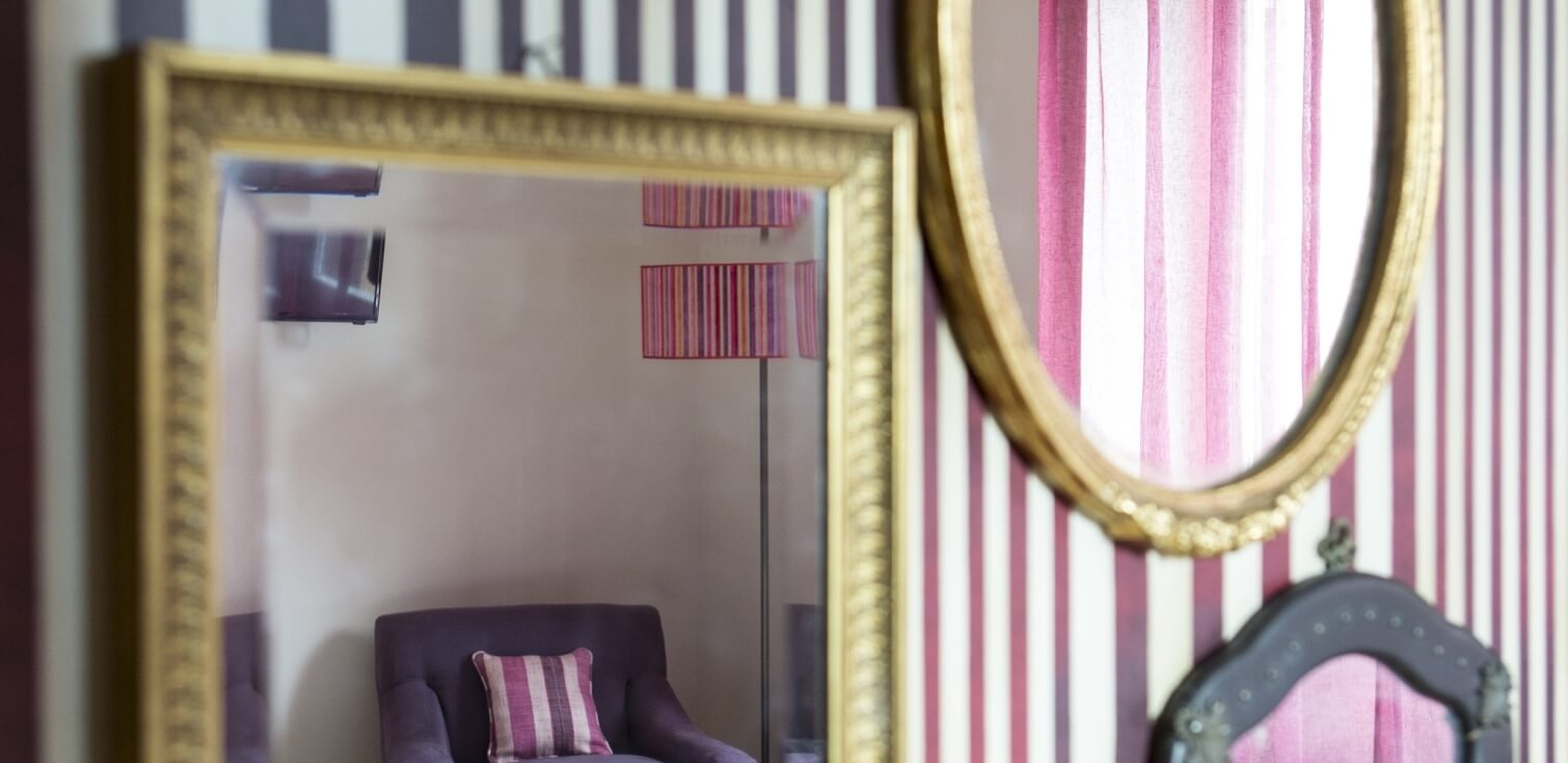 parete con specchi e riflesso di una poltrona viola