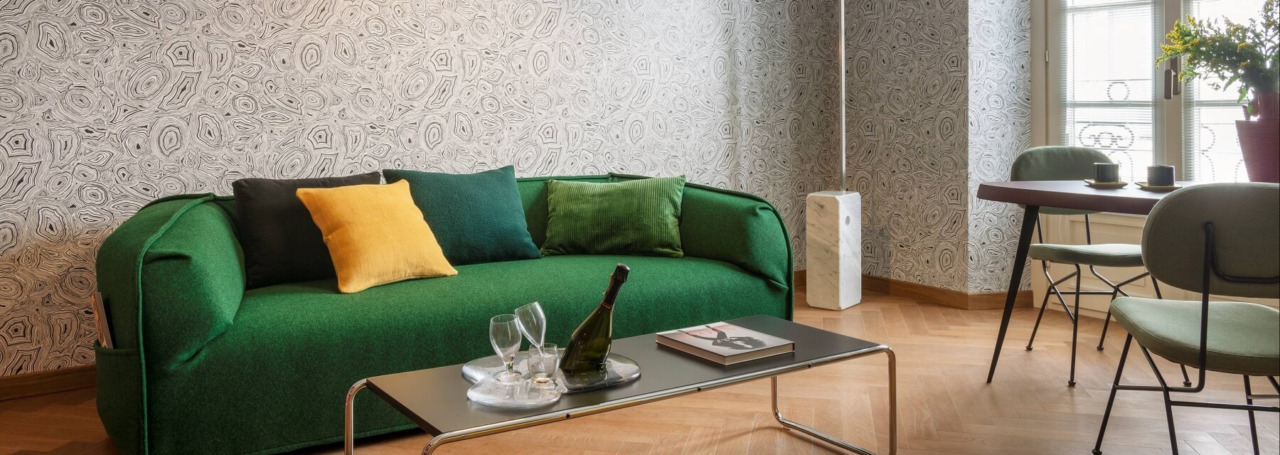 Cozy living room with a green couch, dark brown coffee table, and a dining area featuring a round table and green chairs.