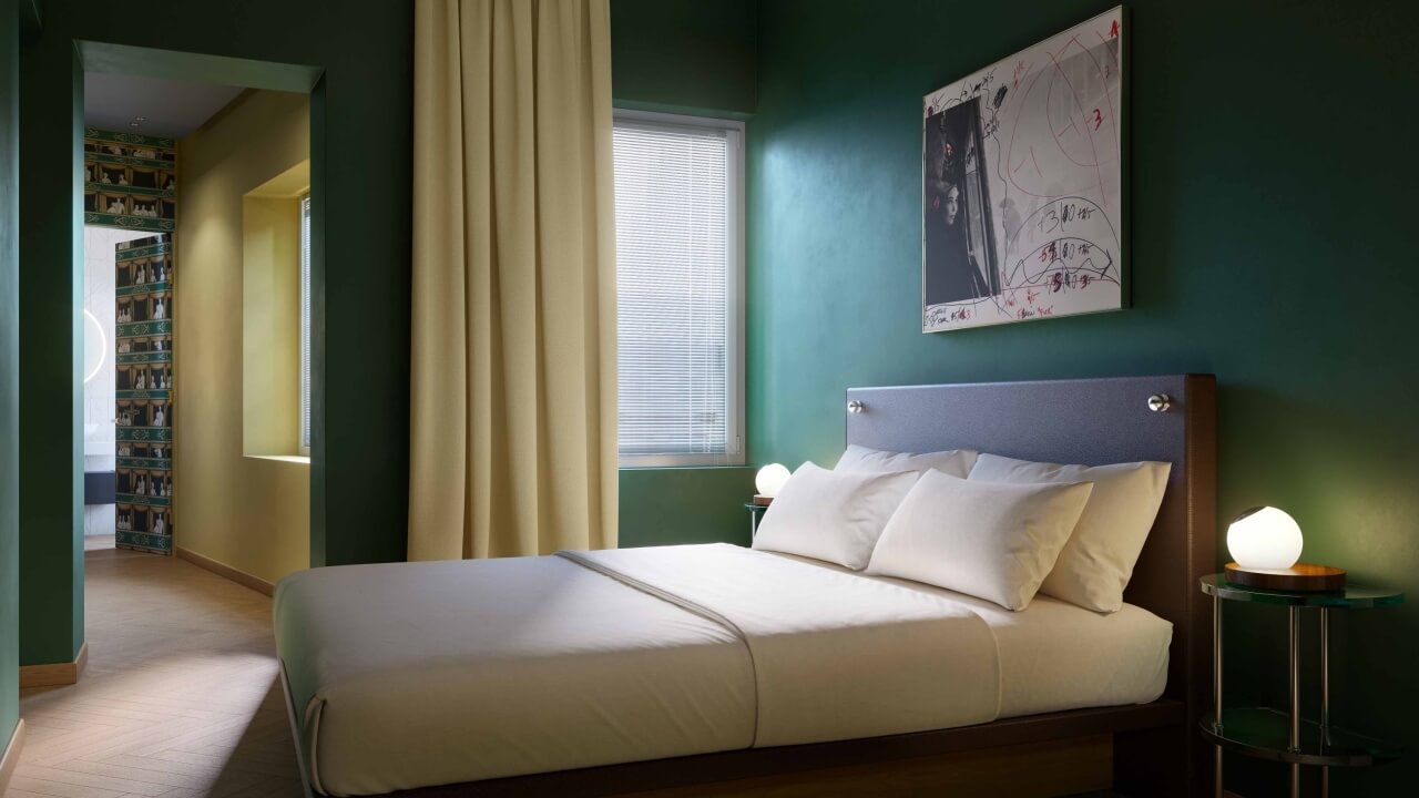 Serene bedroom with dark green walls, elegant bed, glowing lamps, abstract art, and a doorway to a hallway with bookshelves.