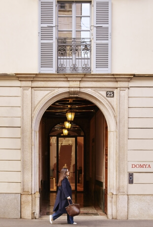 Donna con borsa passa sotto un arco, edificio con numero 25.