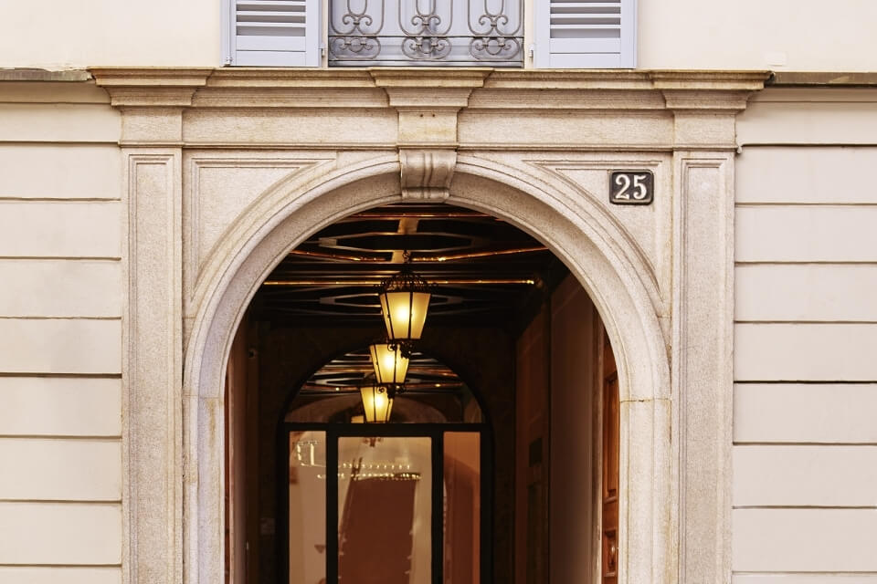 Facciata con arco ornato, finestra decorativa e ingresso illuminato.