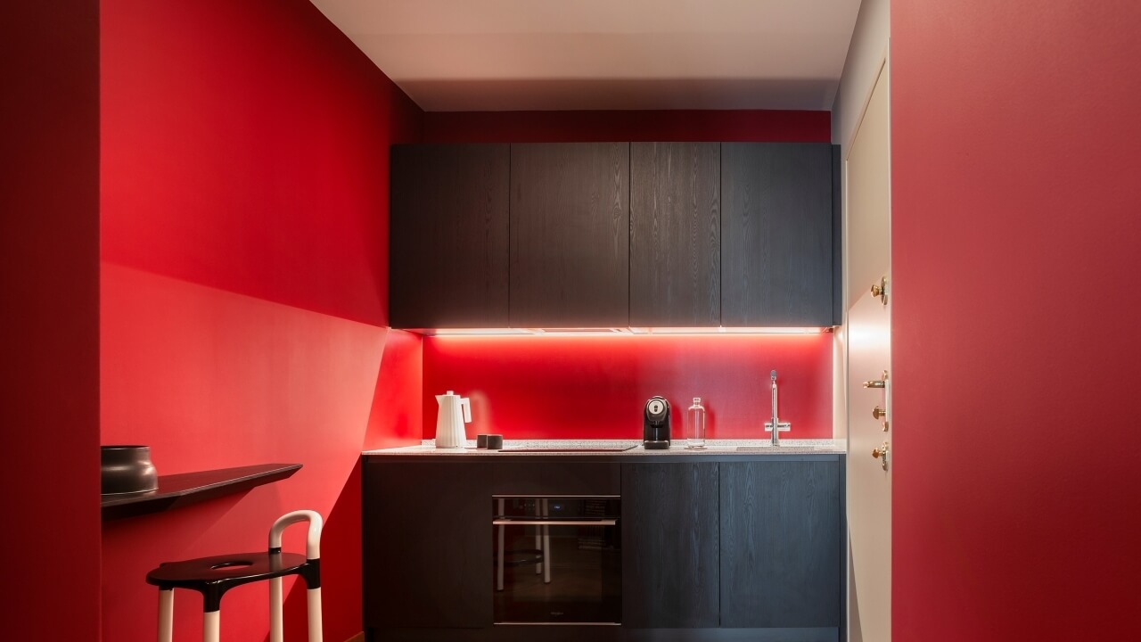 Modern kitchen with red walls, dark wood cabinets, white countertop, and stylish appliances, creating a functional and inviting space.