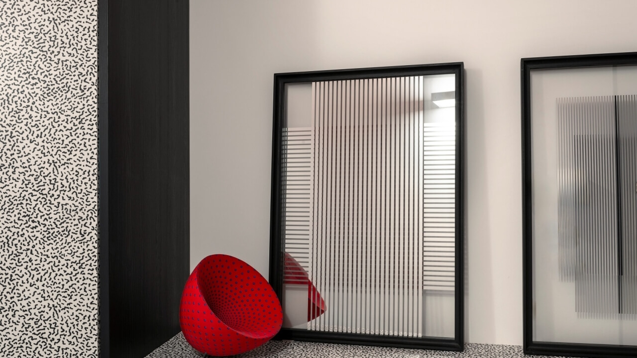 A modern room with white walls, two black-framed mirrors, a red chair, and a patterned wall, featuring a black and white tiled floor.