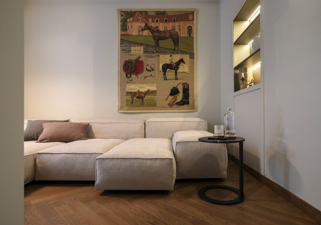 Soggiorno accogliente con divano bianco, tavolino nero, opere d'arte di cavalli e pareti bianche.