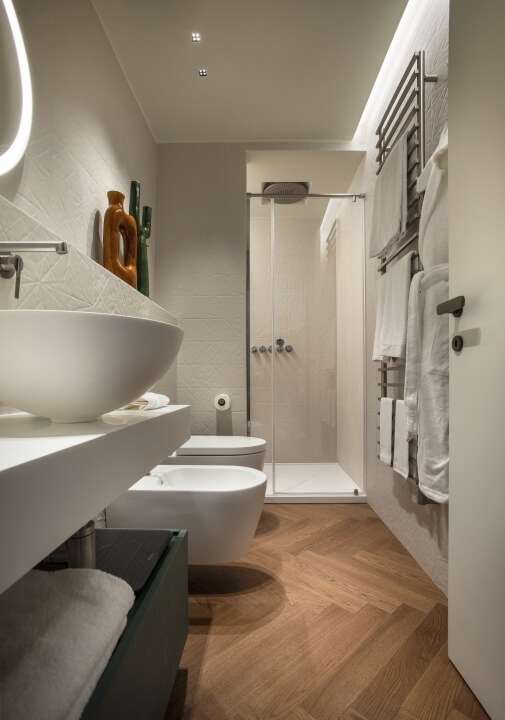 Bagno moderno e luminoso con specchio, lavabo galleggiante, doccia aperta e decorazioni eleganti in un'atmosfera accogliente.