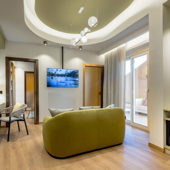 Salon moderne avec canapé jaune, télévision et porte-fenêtre.