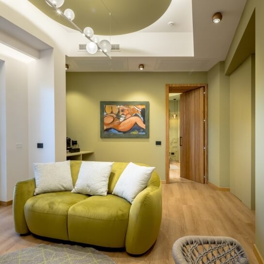 Chambre d'hôtel avec canapé vert, peinture et machine à café.