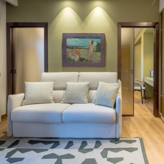 Salon avec canapé clair, peinture de plage et portes vitrées.