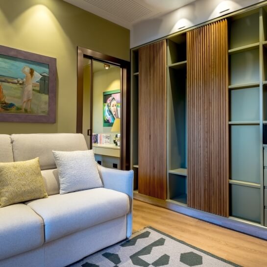 Salon d'appartement avec canapé, étagère intégrée et peinture murale.