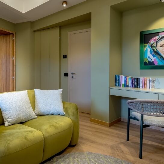 Sofa vert lime avec coussins blancs, bureau et peinture au mur.